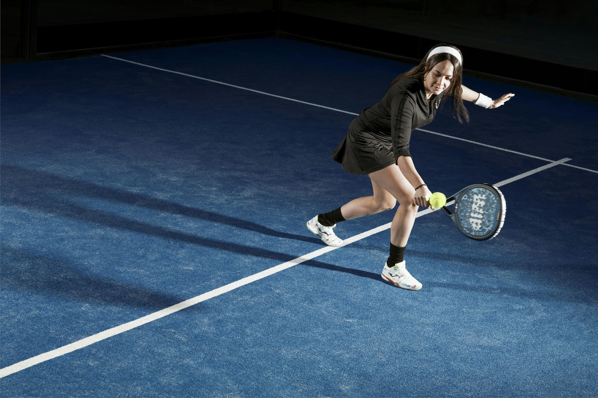 Padelspielerin beim Schlag auf einem blauen Court